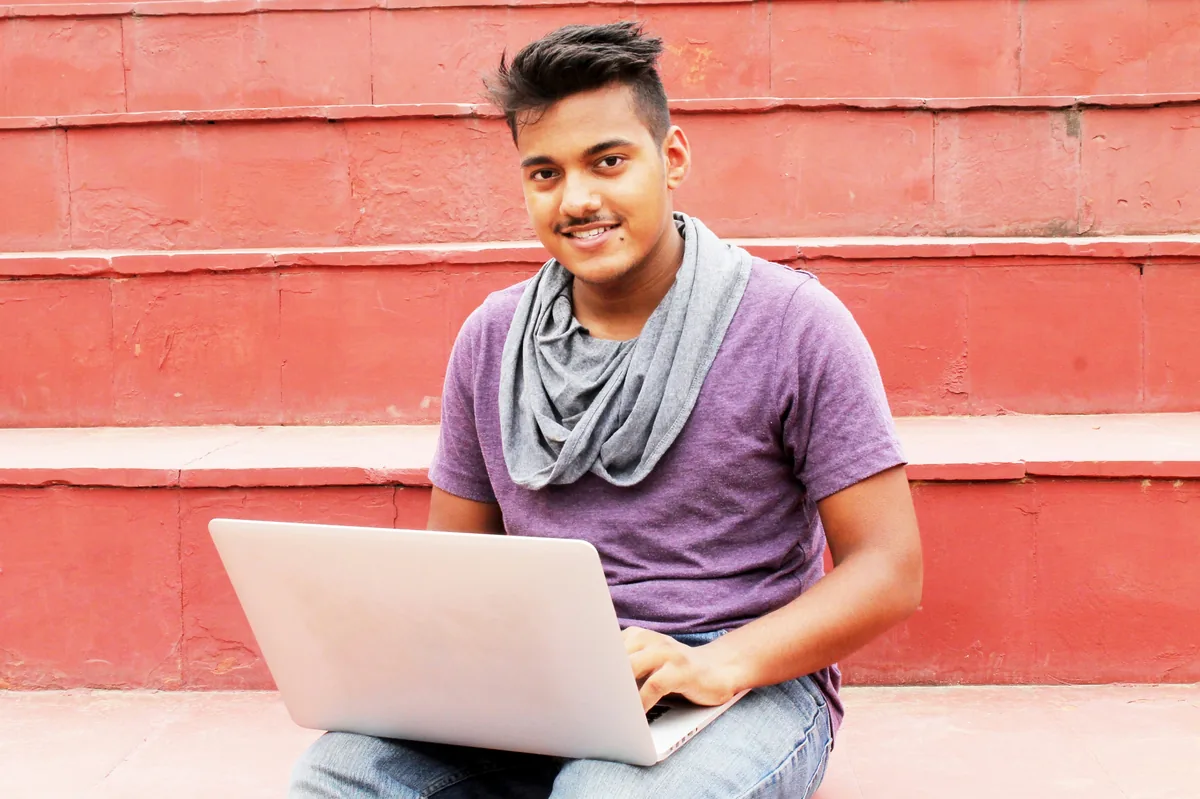 Young man using a laptop while sitting on red outdoor steps
